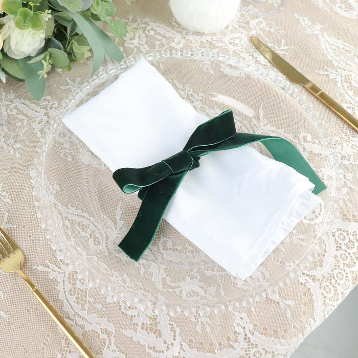 Elegant white napkin tied with a green velvet ribbon on a decorative plate.