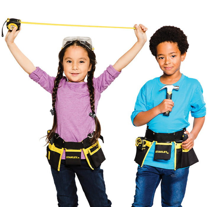 Two kids in work belts and tool gear stand side by side. The girl smiles, holding a measuring tape overhead, while the boy grips a hammer from their Red Toolbox Stanley Jr. 10 Piece Toolset, ready for a building project in casual clothes.