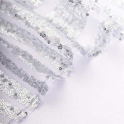 Silver sequin fabric with sheer layers for crafting and decoration.