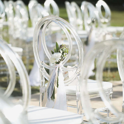 Clear acrylic chair with floral decoration for outdoor event seating.