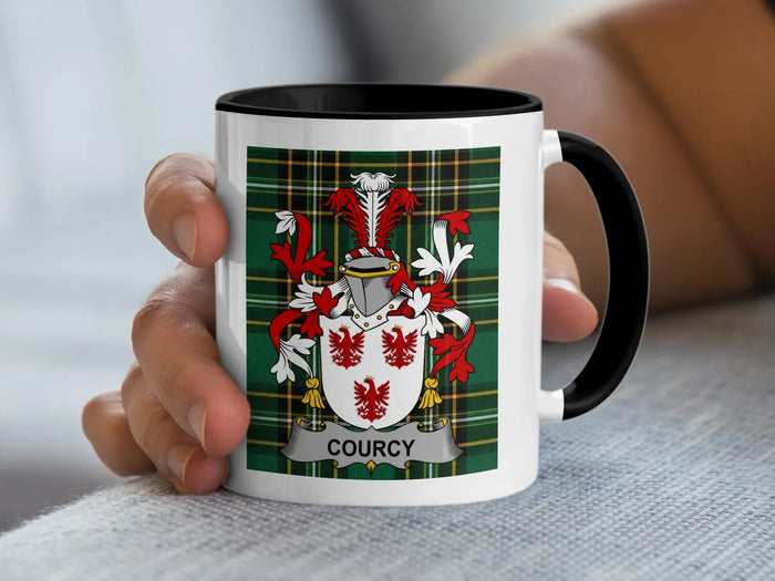 White mug with black rim featuring the Courcy coat of arms on a plaid background.