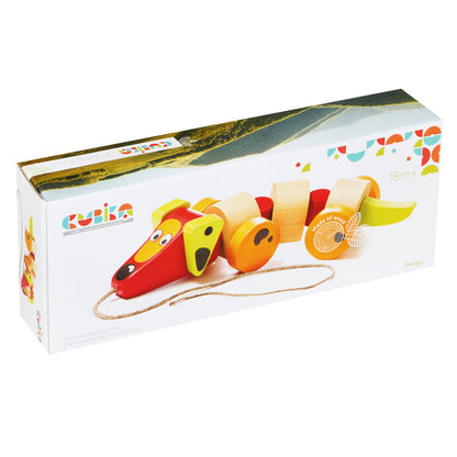 A rectangular box showcases the Cubika Wooden Sausage Dog pull toy in red, yellow, and natural wood. The eco-friendly packaging displays the Cubika brand and notes it's suitable for children aged 18 months and up.