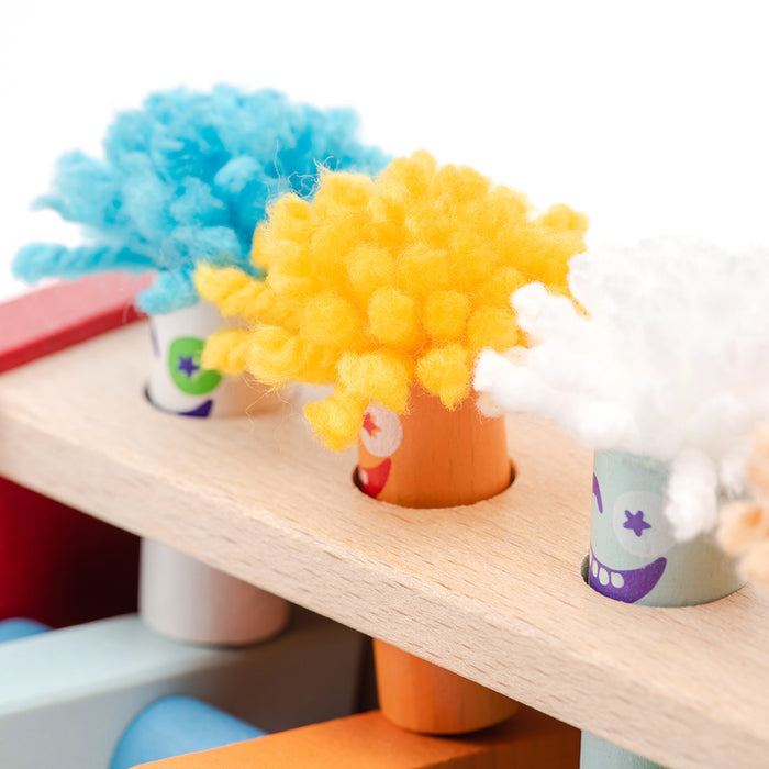 Cubika Wooden Toy Jumping Clowns by Cubika feature blue, yellow, and white wooden clowns with yarn hair in a light wood frame. Each eco-friendly toy has a painted smile and helps develop motor skills up close.