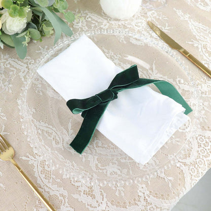 Elegant white napkin tied with a green velvet ribbon on a decorative plate.