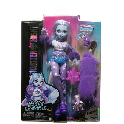 The Mattel Monster High Abbey Doll features purple and blue hair, a winter-themed outfit, pet wooly mammoth, furry purple bag, snowflake accessory, and comes in Monster High-branded packaging with stylish artwork.
