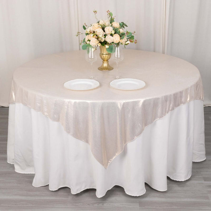 Round table set with a beige tablecloth, plates, and a floral centerpiece.