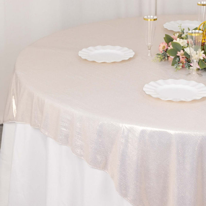 Elegant round table with shimmering beige tablecloth and white plates.