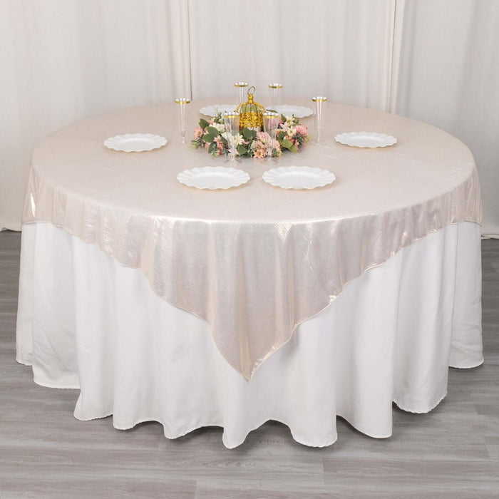 Elegant round table set with a beige tablecloth and decorative centerpieces.