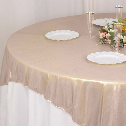 Elegant round tablecloth in gold on a dining table with white plates and floral centerpiece.