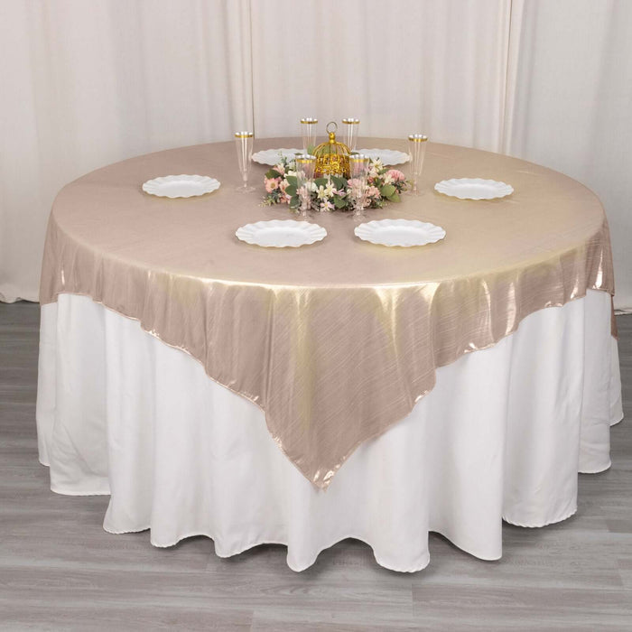 Round table set with beige tablecloth, white plates, and floral centerpiece.