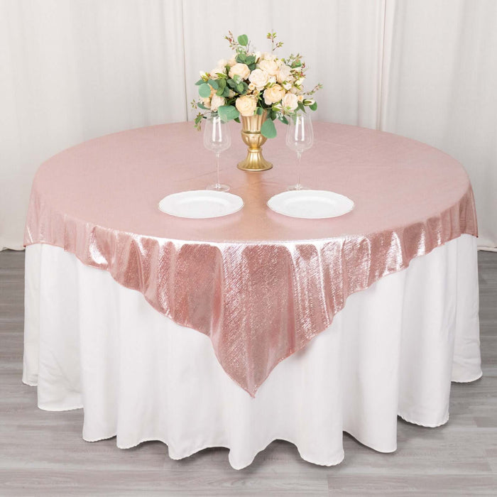 Rose gold tablecloth with elegant floral centerpiece and dinnerware.