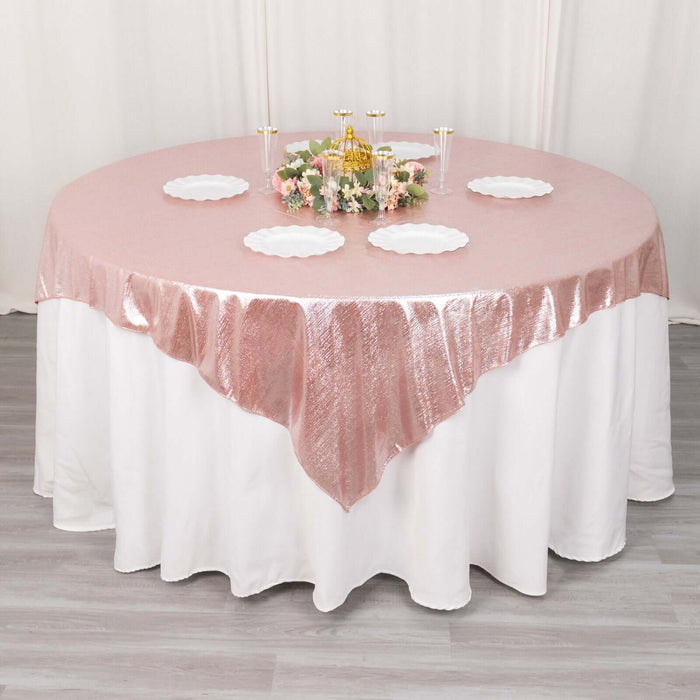 Round table set with a pink tablecloth and decorative centerpiece.