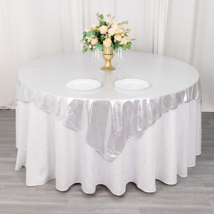 Round table set with silver tablecloth and floral centerpiece.