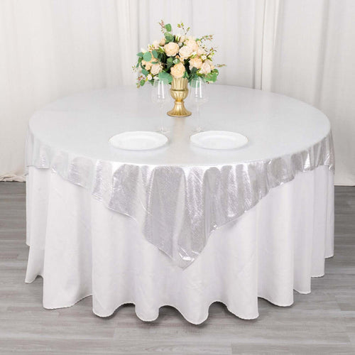 Round table set with silver tablecloth and floral centerpiece.