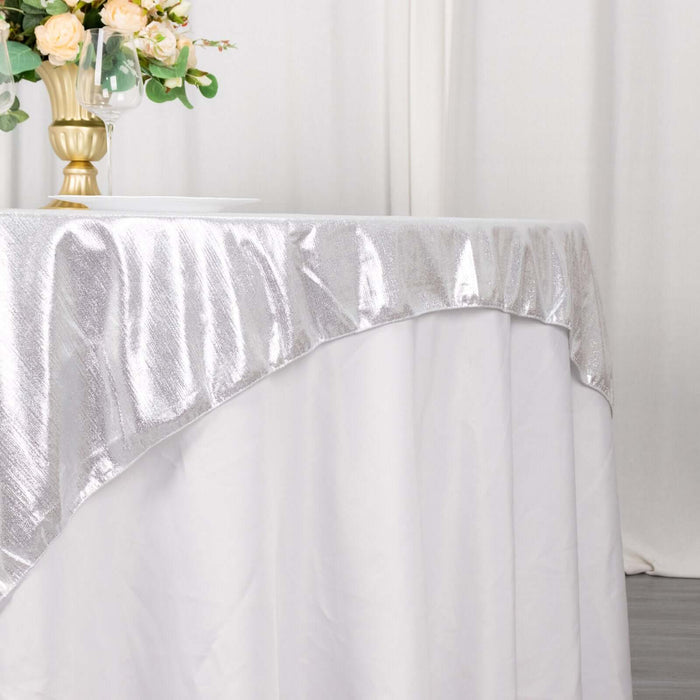 Silver tablecloth draped elegantly on a table with floral centerpiece.