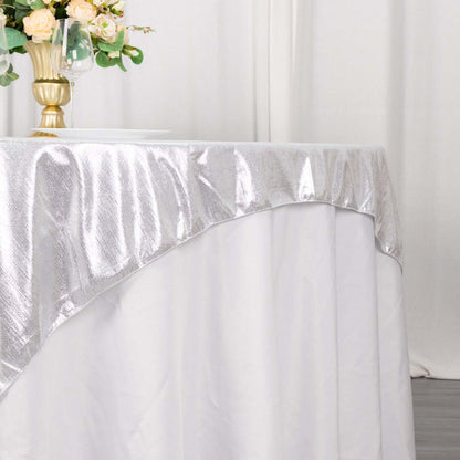 Silver tablecloth draped elegantly on a table with floral centerpiece.