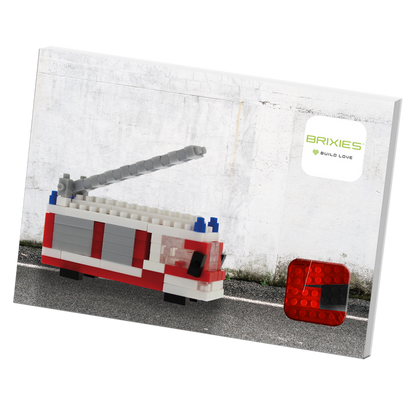A box featuring a BRIXIES Postcard Fire Truck building set made of bricks, displayed against a white wall with the Brixies logo and "Build Love" tagline—perfect as a mailable postcard.