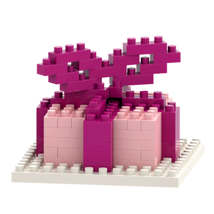 The Brixies Postcard Gift features a 3D gift box made from interlocking micro bricks in shades of pink with a large bow, displayed on a white baseplate. This unique model is part of the creative Brixies Postcard series.