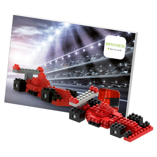 The Brixies Postcard Racing Car is a micro brick model in red and black, showcased with a racing-themed backdrop, track lights, and Brixies logo—a perfect mini build kit for fans of race car postcards.