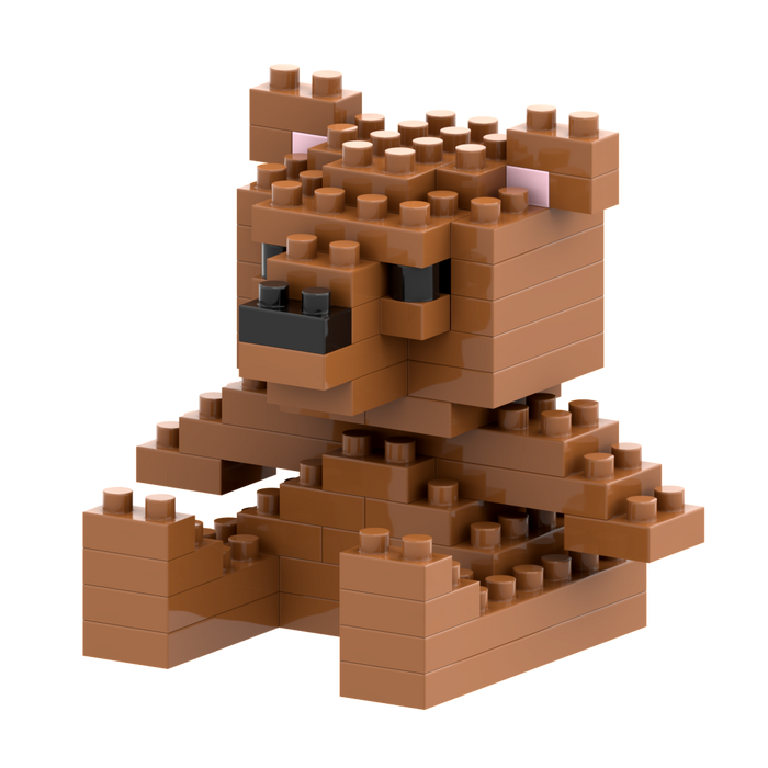 The Brixies Postcard Teddy Bear is a small 3D figure made of interlocking brown bricks, featuring blocky legs, arms, ears, a short tail, and a black nose with white and black eyes.