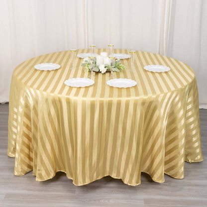 Round gold striped tablecloth on a dining table with decorative plates and candles.
