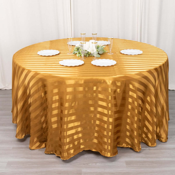 Gold striped round tablecloth on a dining table with white plates and decor.