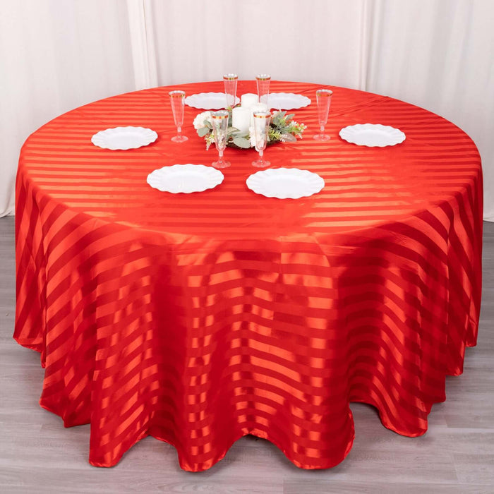 Red striped tablecloth draped over a round table set for a meal.