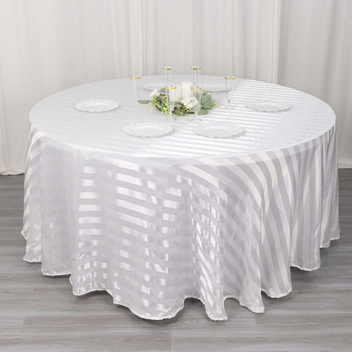 Elegant round table with a striped white tablecloth and decorative centerpieces.