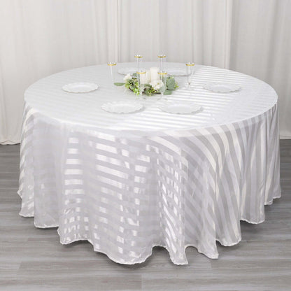 Elegant round table with a striped white tablecloth and decorative centerpieces.