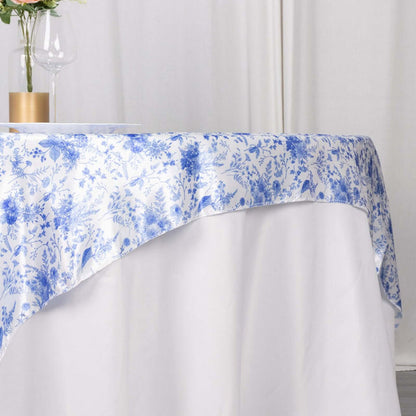 Floral blue and white tablecloth draped over a table with a glass and vase.