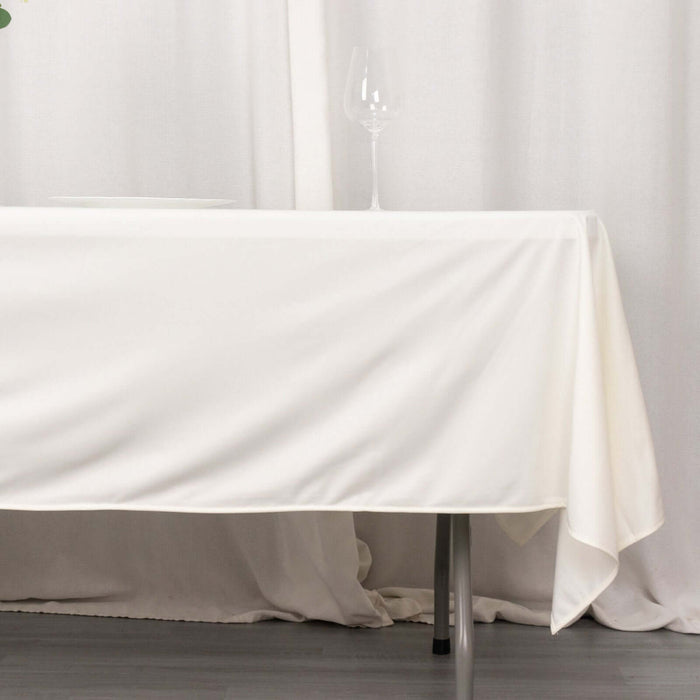 White tablecloth draped over a table with a wine glass on top.