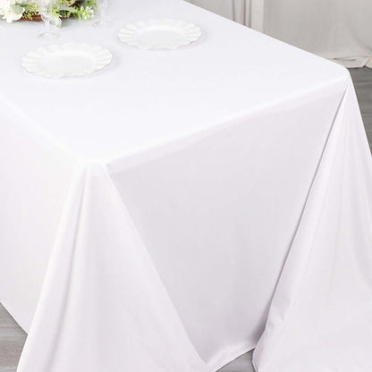White tablecloth draped over a table with two empty plates.