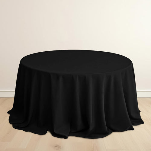 Black round tablecloth on a wooden floor.