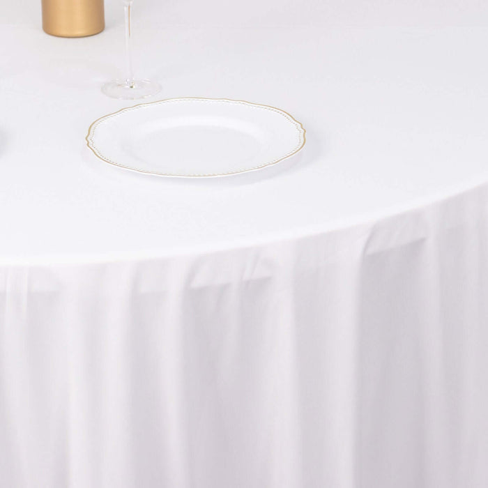 Elegant white plate with gold rim on a table with a white tablecloth.