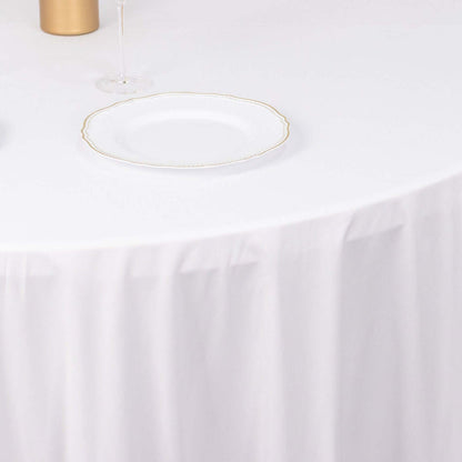 Elegant white plate with gold rim on a table with a white tablecloth.