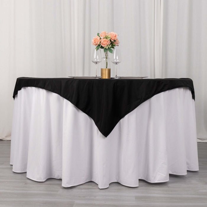 Elegant round table dressed in white and black linens with floral centerpiece.