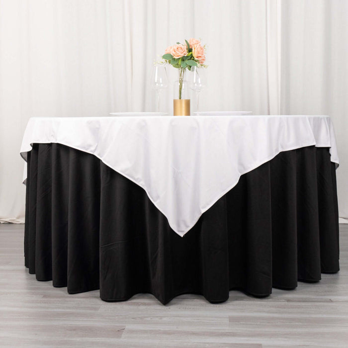 Elegant round table with black and white tablecloth, adorned with flowers and glasses.