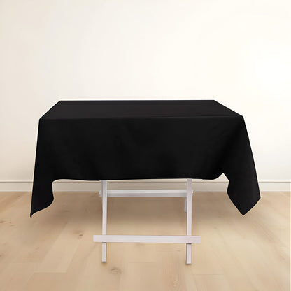 Black tablecloth draped over a white folding table in a minimalist setting.