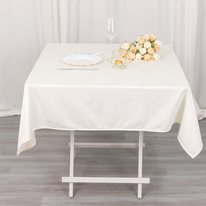 White tablecloth draped over a table with a floral centerpiece and glassware.