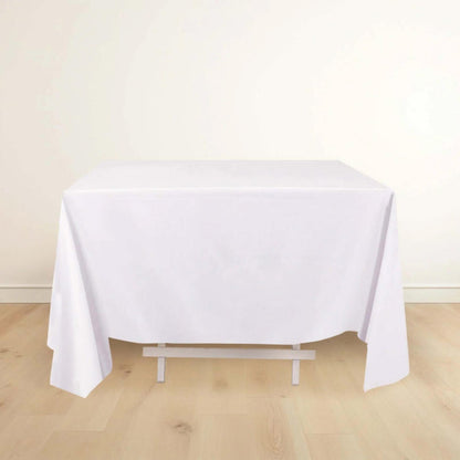 White tablecloth draping over a table on a light wooden floor.