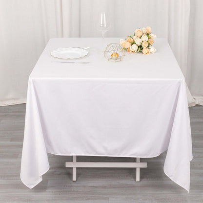 White tablecloth draped elegantly over a table with floral centerpiece and glassware.