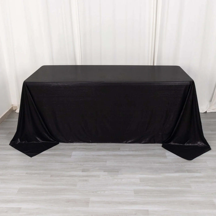 Black table draped with a sleek tablecloth for event styling.