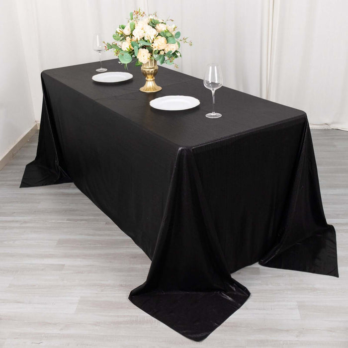 Elegant black tablecloth draped over a dining table with floral centerpiece and dinnerware.
