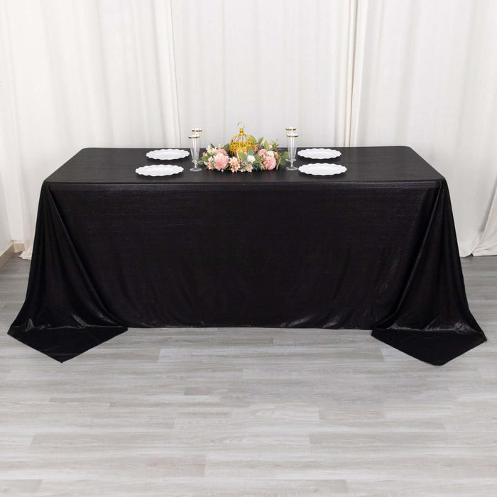 Elegant black tablecloth draped over a table with floral centerpiece and plates.