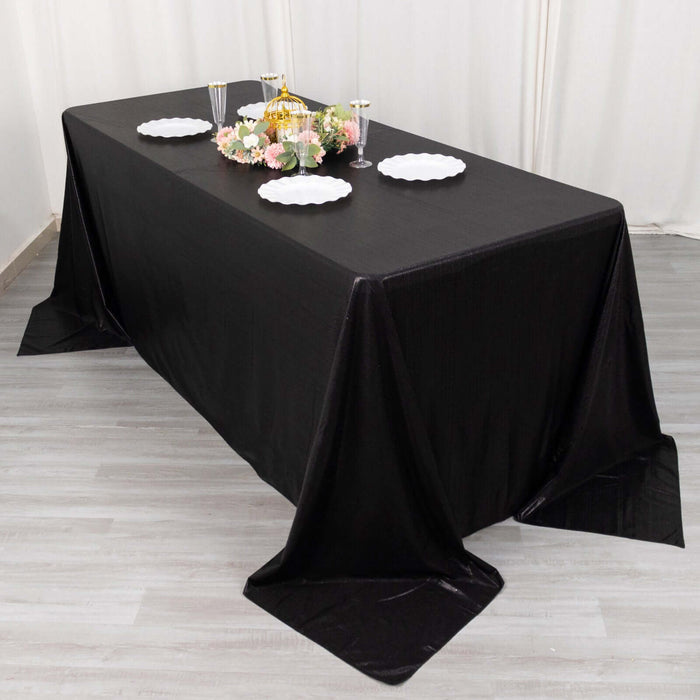 Black tablecloth draped over a rectangular table set for an elegant dining occasion.