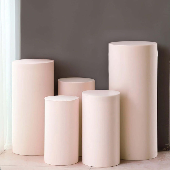 Set of five pink pedestals in varying heights against a gray wall.