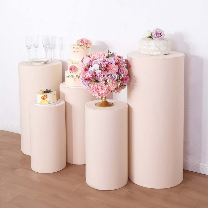 Decorative display pedestals in various sizes with floral arrangements and cakes.