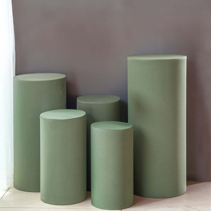 Green cylindrical display pedestals in various heights against a neutral backdrop.