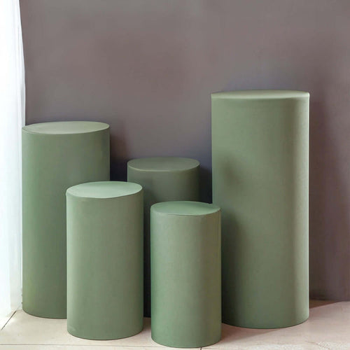 Green cylindrical display pedestals in various heights against a neutral backdrop.