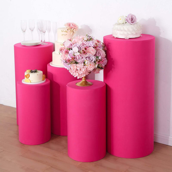 Colorful pink display pedestals for events, showcasing cakes and floral arrangements.